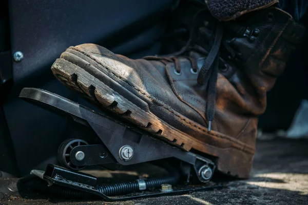 Kaki pekerja dalam sepatu besar atau boot menekan pedal penggali industri atau traktor — Stok Foto