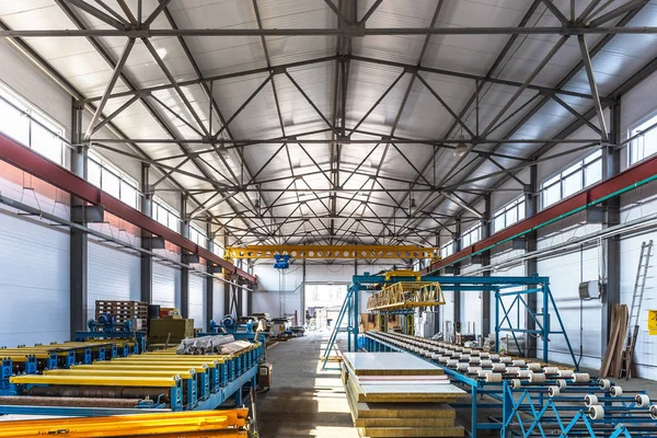 Sandwich manufactory panel production line. Equipment machine tools and roller conveyor in large hangar or workshop
