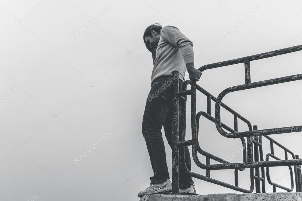 Depressed and upset man is going to jump from bridge standing on edge. Suicide concept