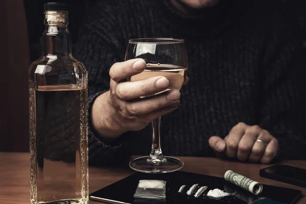 Man holds glass of whiskey and uses cocaine drugs. Drug abuse and alcoholism concept — Stock Photo, Image