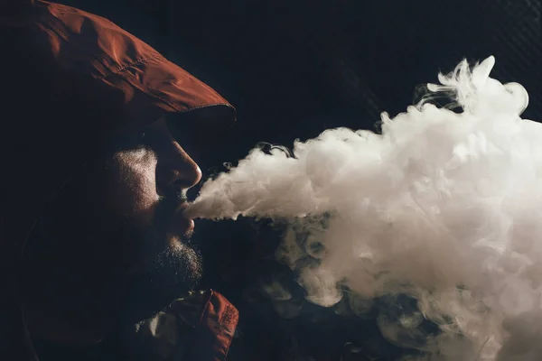 Ember vape e-cigaretta, e-folyadék, közelkép, lélegzik, gőz vagy pára a sötét háttér nagy felhő. Vaping koncepció — Stock Fotó