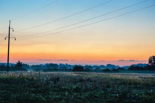 Lignes électriques au lever du soleil brumeux sur firld — Photo