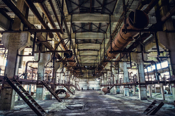 Ruins of abandoned industrial factory, large warehouse or hangar building with rusty equipment and machine tools, dark toned