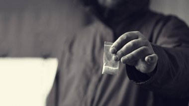 Drug dealer offers cocaine dose or another drugs in plastic bag, drug addiction on party concept, selective focus clipart