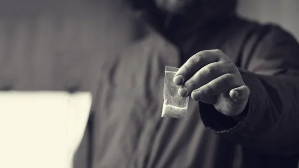 Έμπορος ναρκωτικών προσφέρει δόση κοκαΐνης ή άλλο φάρμακα σε πλαστική σακούλα, εθισμός στα ναρκωτικά στην έννοια κόμμα, επιλεκτική εστίαση — Φωτογραφία Αρχείου