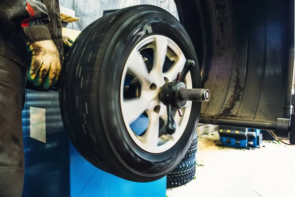 Mechanic balancing wheel with computer machine balancer at car service garage workshop — Stock Photo, Image