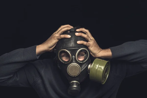 Uomo in maschera antigas tiene le mani dietro la testa, emozione di panico e catastrofe o concetto di disastro — Foto Stock