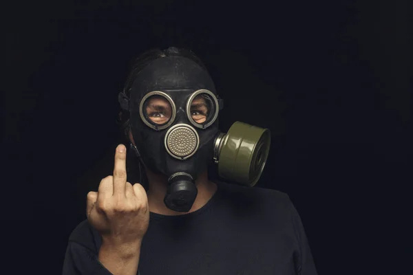 Portrait of man in gas mask on dark background, shows middle fingers sign by one hands — Stock Photo, Image