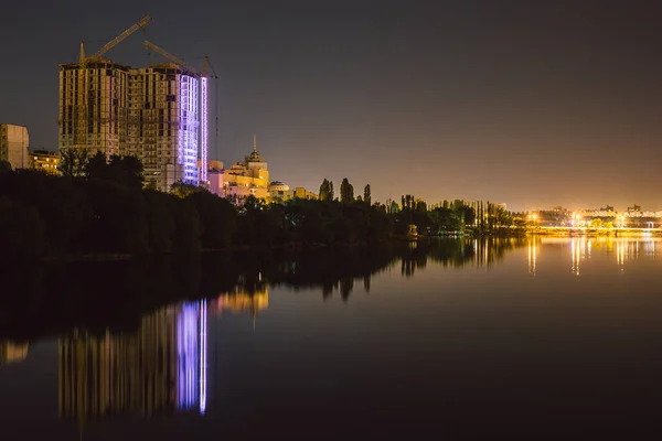 Reflejo de gran casa en construcción con iluminación en agua del lago paisaje nocturno urbano — Foto de Stock