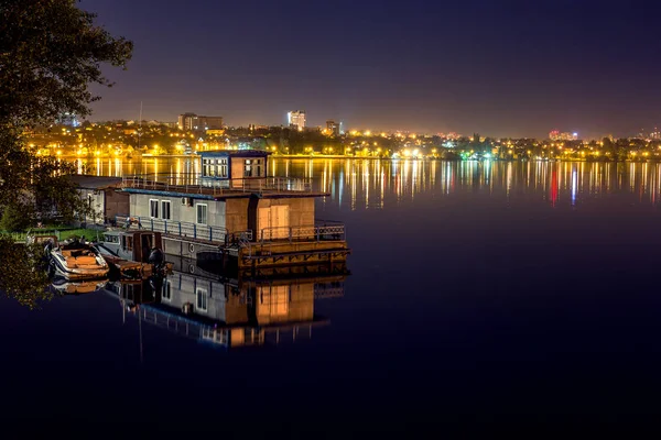 Lodní stanice s domem na vodě na jezero nebo řeka v noci, odraz světla noční město ve vodě — Stock fotografie