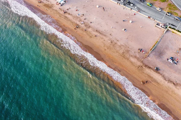 Blick von oben auf den Strand des italienischen Urlaubsortes mit Sand und schäumenden Meereswellen bei Sonnenuntergang. ostia lido bei rom, italien — Stockfoto