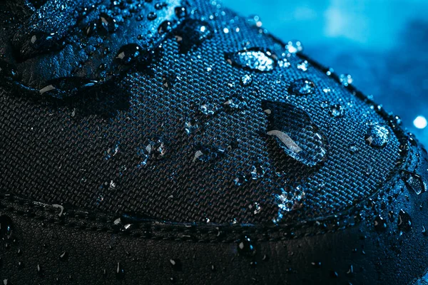 Water drops on waterproof membrane fabric of shoes surface, macro shot. New waterproofing technology for wear and footwear for active lifestyle