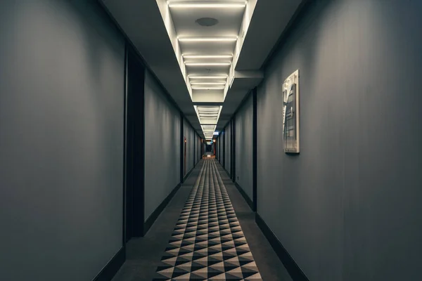 Corredor oscuro con iluminación en el techo. Vista del túnel del pasillo vacío del hotel en tiempo nocturno — Foto de Stock