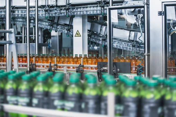 Botellas de plástico con jugo orgánico fresco en cinta transportadora automática o línea en fábrica de bebidas o en el interior de la planta con equipos modernos de máquinas industriales —  Fotos de Stock