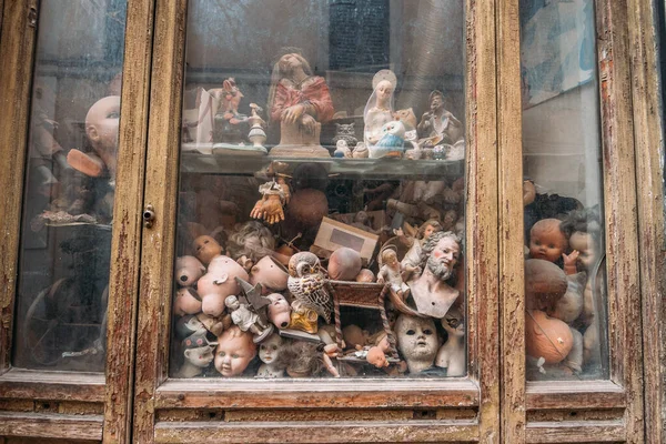 Майстерня покинутих ляльок, багато пластикових частин дитячих ляльок позаду брудного скла — стокове фото