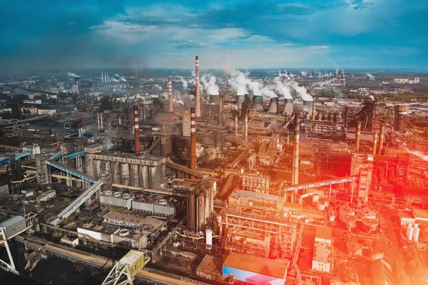 Aerial view of Factory or Plant Industrial Area with many pipes or chimneys with smoke in red sunlight flare. Heavy industry, landscape from drone