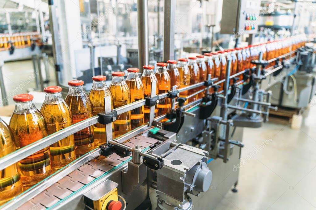 Conveyor belt, juice in bottles on beverage plant or factory interior, industrial production line