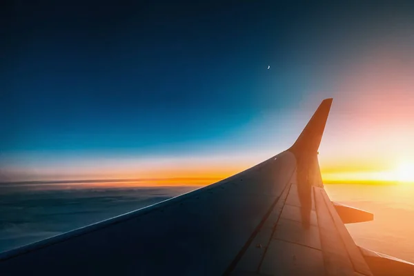 Sunset from airplane window view. Aircraft wing from illuminator view