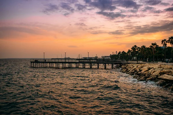 Pier no parque Molos Promenade ao pôr do sol na cidade de Limassol, Chipre. Linda noite mediterrânea mar resort — Fotografia de Stock