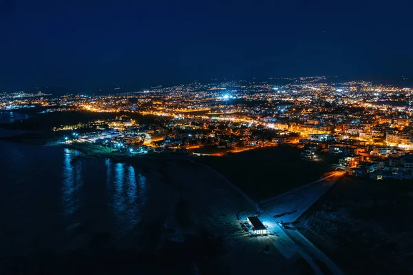 Vista panorâmica aérea de Paphos, Chipre à beira-mar de cima à noite de drone. Bela noite mediterrânea paisagem marinha com edifícios iluminados e reflexos de luzes na água do mar — Fotografia de Stock