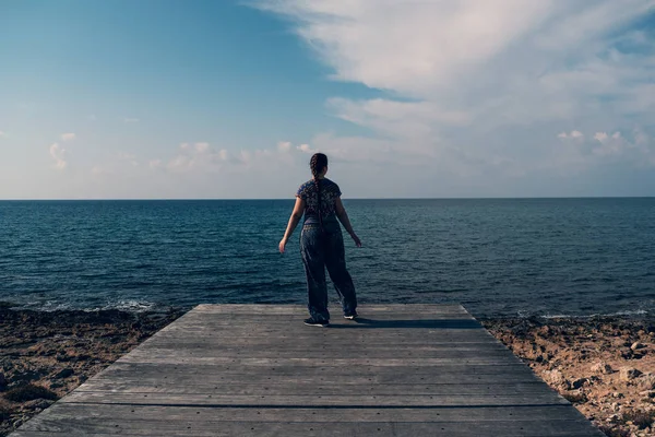 Akdeniz 'deki ahşap iskelede ve mavi gökyüzü arka planında güzel bir kız. Seyahat kavramı — Stok fotoğraf