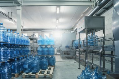 İçindeki su üretim fabrikasındaki paletlerin üzerindeki saf içme suyu şişeleri ya da galonlar.