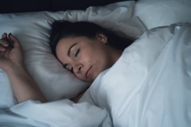 Genç güzel kız veya kadın gece büyük yatakta yalnız uyku