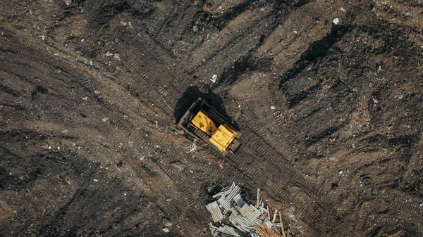 Aerial top view of a construction site or country dump with yellow excavator or bulldozer, heavy equipment, drone photo — Stock Photo, Image
