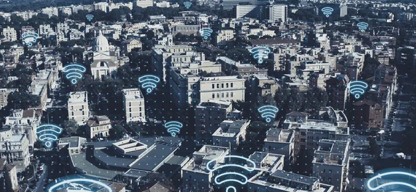 Digital city of future concept. Aerial view of European cityscape with wireless communication networks WI-FI neon symbols, IoT Internet of Things, Big Data web connections in all buildings and houses