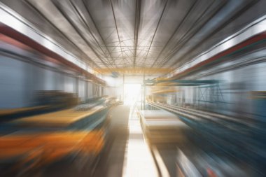 Endüstriyel fabrika deposu. İçi bulanık hareket ve güneş ışığıyla dolu.