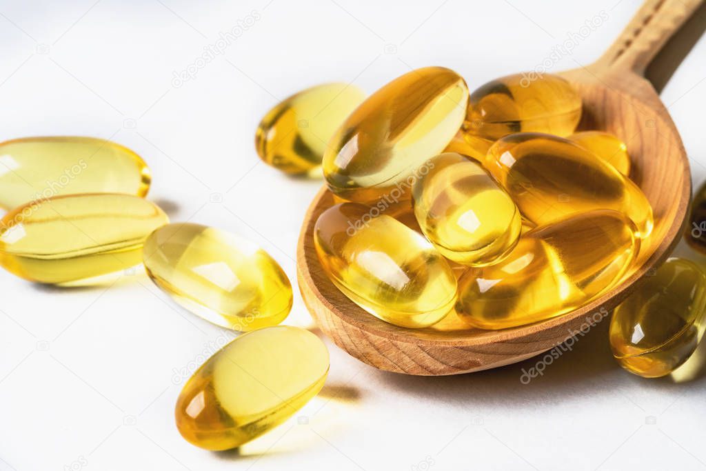 Omega 3 yellow capsules in wooden spoon on white background. EPA and DHA are two types of Omega-3 fats Essential Fatty Acids