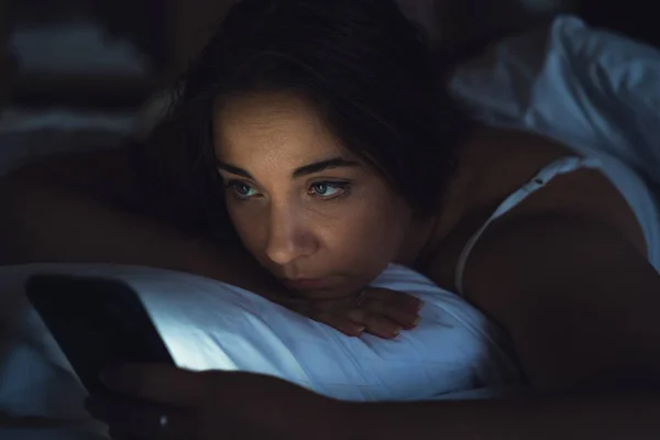 Nő használ okostelefon az ágyban éjszaka, közelről — Stock Fotó