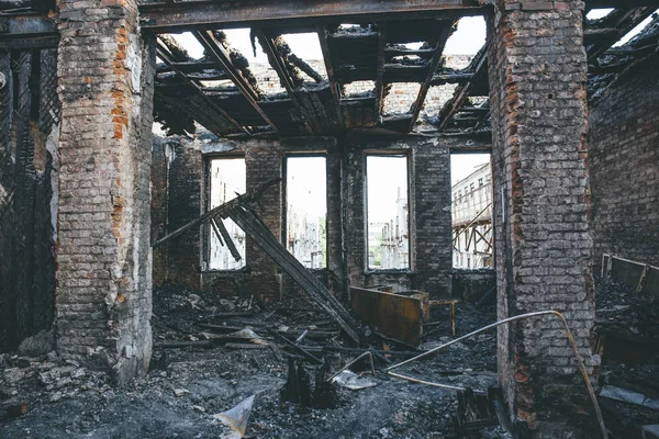 Burnt house interior inside, burned ruined room, remains of furniture in black soot on floor. Fire or war consequences concept