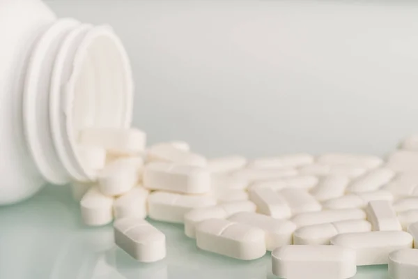 Pastillas de medicina blanca derramadas en la mesa del frasco de pastillas. Medicamentos drogas o suplementos o adicción a los opioides de analgésicos, macro con enfoque selectivo — Foto de Stock