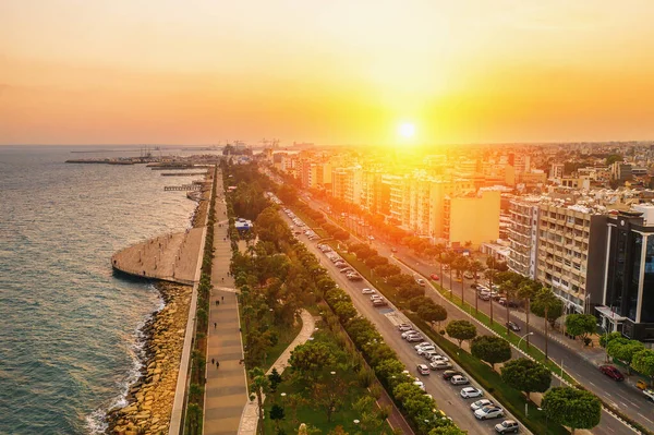 Vista aérea da costa da cidade de Limassol, em Chipre. Caminho a pé Molos Park com palmeiras, Mar Mediterrâneo e horizonte urbano ao pôr do sol, drone foto — Fotografia de Stock