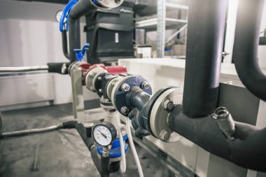 Birçok borusu, metal tüpleri ve otomatik kontrol cihazları olan ısıtma sistemi.