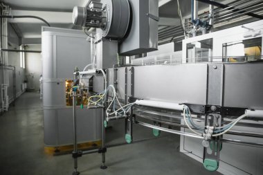 Hayvan preformlarından plastik şişe üfleme makinesi, fabrikanın iç kısımlarında endüstriyel taşıyıcı bant