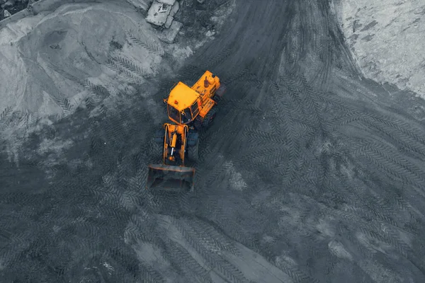 Yellow excavator or bulldozer in coal open cast mining quarry, aerial top view from drone — Stock Photo, Image