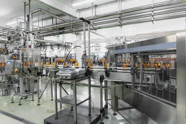 Industrial interior of natural juice plant production. Conveyor belt, filled bottles on beverage factory, industry production line