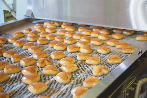 Pastry on conveyor line, food production factory, close up