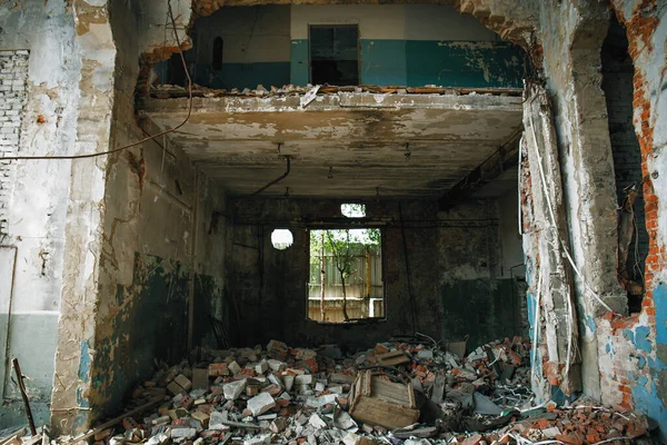 Ruined abandoned building with large pills of concrete garbage, aftermath of natural disaster or war — Stock Photo, Image