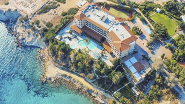 Deniz kıyısındaki otelin hava manzarası mavi Akdeniz suyu, Kıbrıs tatil beldesinin insansız hava aracı fotoğrafı.