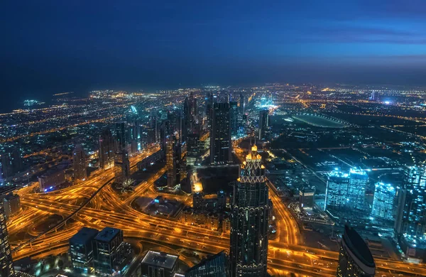 Junção rodoviária urbana na cidade noturna Dubai, Emirados Árabes Unidos. Tráfego no centro da cidade iluminado com panorama de arranha-céus e edifícios modernos do distrito de negócios de Dubai, vista de cima — Fotografia de Stock
