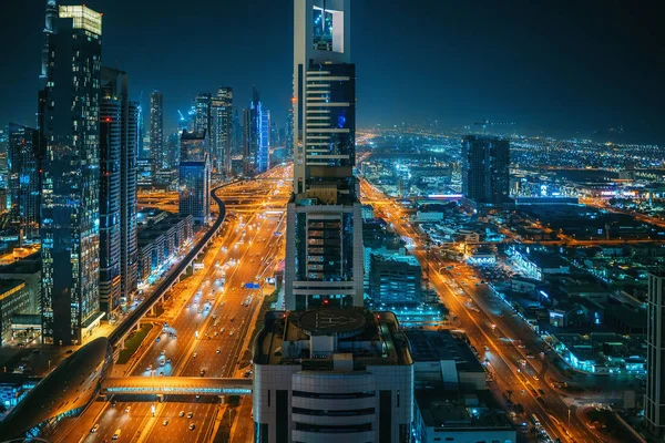 Linda noite Dubai skyline centro da cidade, Emirados Árabes Unidos. Vista aérea de cima de rodovias com tráfego de automóveis e arranha-céus edifícios — Fotografia de Stock