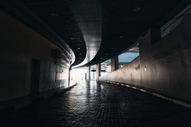 Alışveriş merkezindeki araba parkındaki karanlık yeraltı tünelinden aydınlığa çık