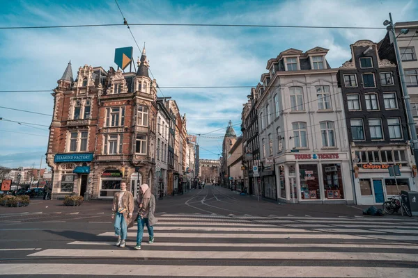 Amsterdam, Países Bajos - 18 de marzo de 2020: Calles medio vacías del centro histórico de Ámsterdam, pocas personas y turistas en las calles, ciudad en cuarentena debido al brote de infección por Coronavirus — Foto de Stock