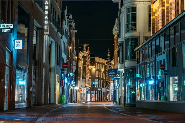 Amsterdam, Países Bajos - 18 de marzo de 2020: Calle comercial vacía con tiendas cerradas por la noche en el centro turístico de Ámsterdam, ciudad en cuarentena desde Coronavirus — Foto de Stock