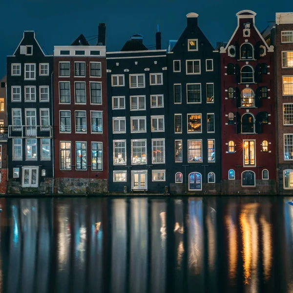 Berühmte Tanzhäuser und Gebäude in Amsterdam mit Spiegelung im Kanalwasser in der Nacht, schöne europäische Landschaft — Stockfoto