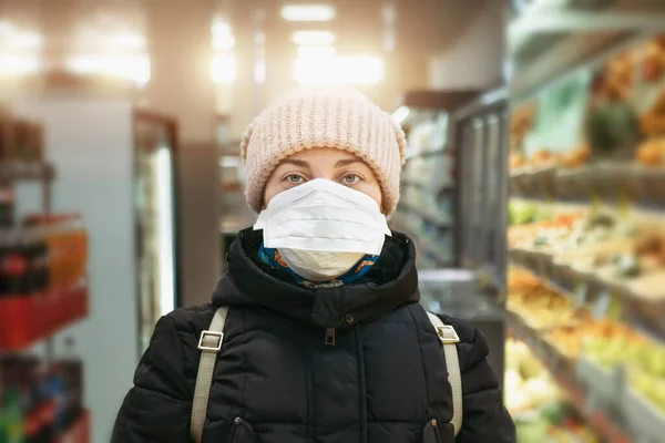 医療用マスクのスーパーマーケットの若い女性がカメラのポートレートを見ています。コロナウイルスパンデミック｜Covid-19ウイルス — ストック写真