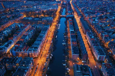 Deniz kanalları, aydınlatılmış yollar ve tarihi binalarla Amsterdam 'ın akşam manzarası, Hollanda
